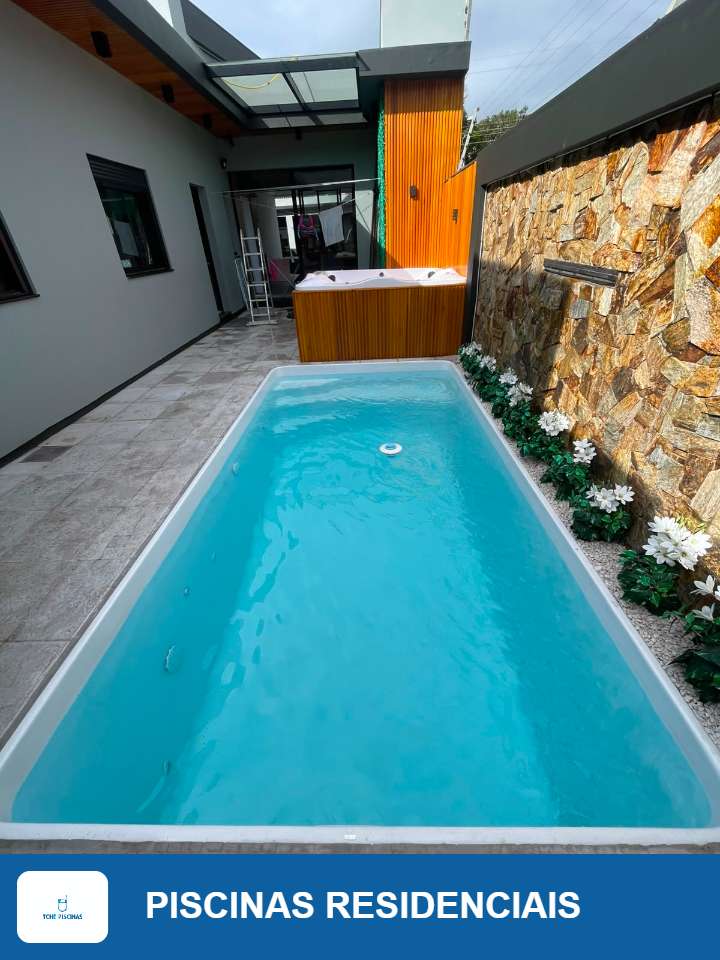 Piscina residencial com parede de pedra e jardim ao redor